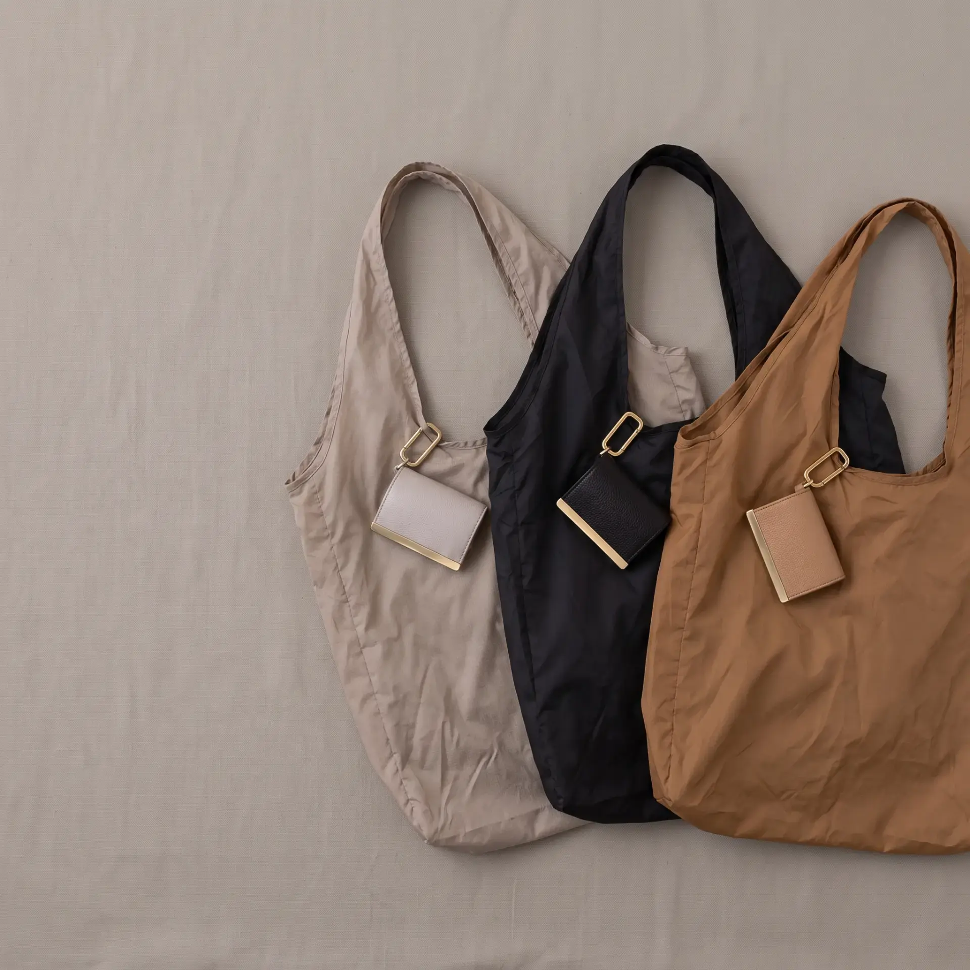 Three cliptote bags in sand, black and tan with gold hardware
